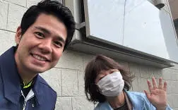 晴天の下で男性3人が外で肩を並べて笑顔を見せている